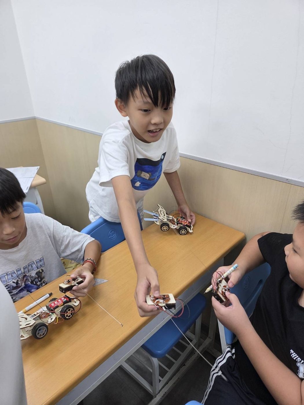拿著自己組好的木頭遙控車的男孩