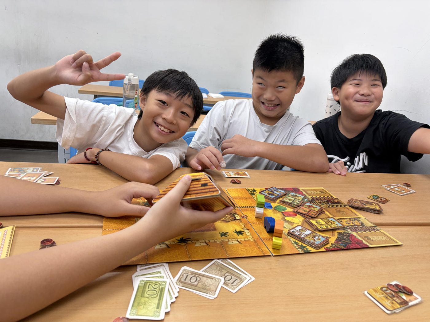 桌遊課上比出勝利手勢的三個男孩